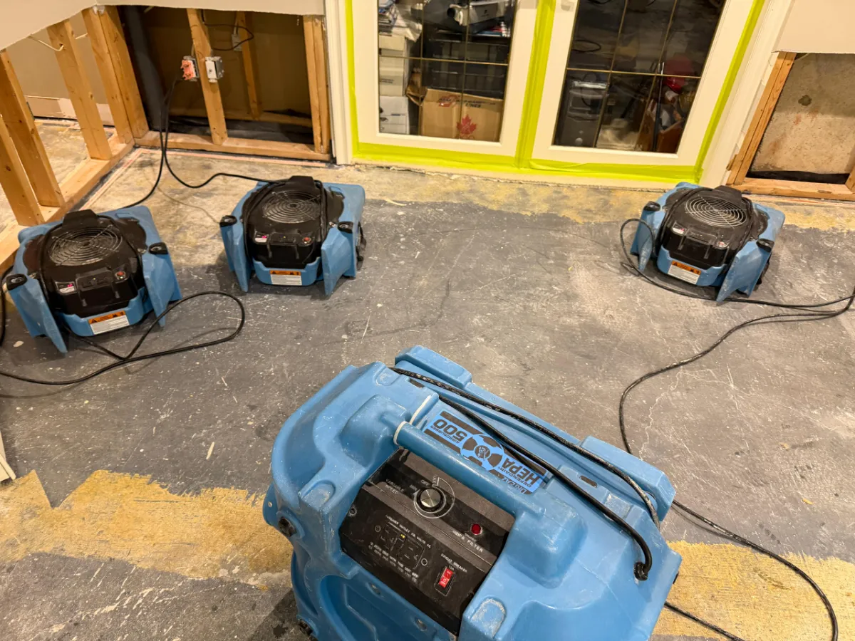 Dehumidifier and air mover drying a room with the windows taped off