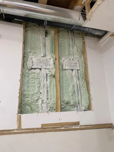 Section of drywall cut out to expose the framing and insulation behind it