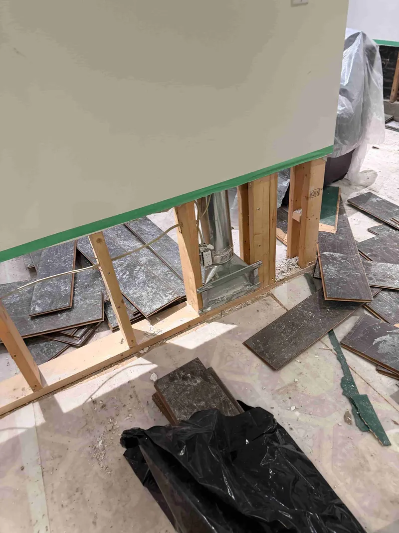 Slate tile flooring removed after water damage, exposed subfloor framing