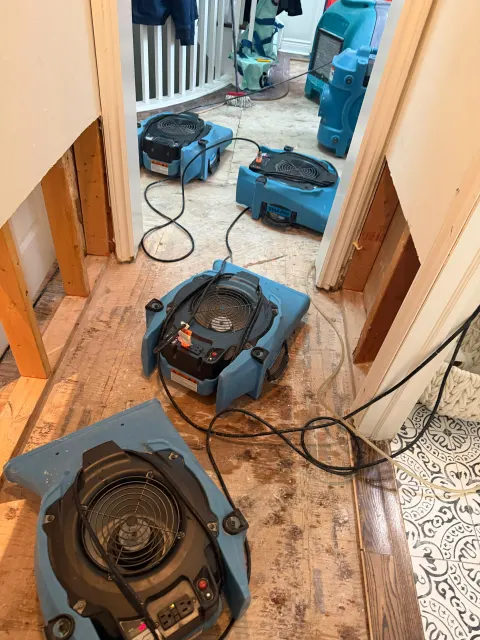 Air movers drying a hallway after the lower drywall was cut out