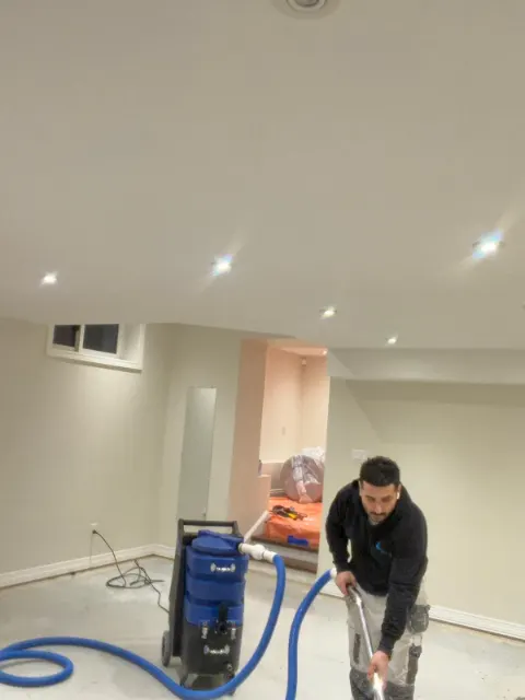 Technician extracting water from a finished basement floor with a portable extractor