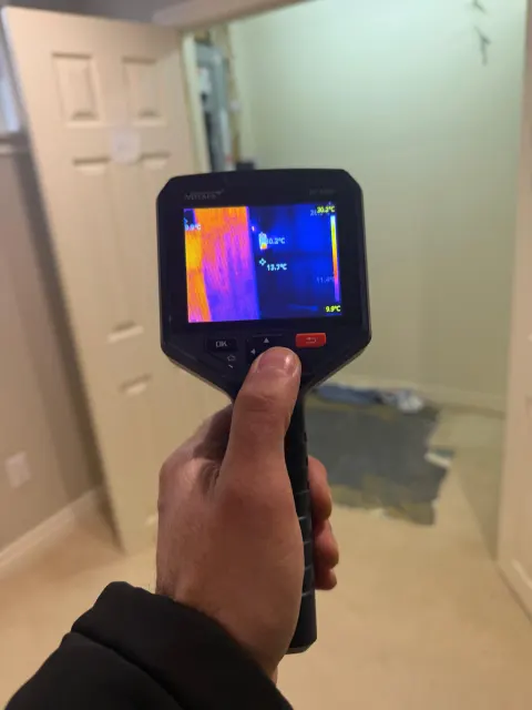 Thermal camera checking a doorway wall for hidden moisture