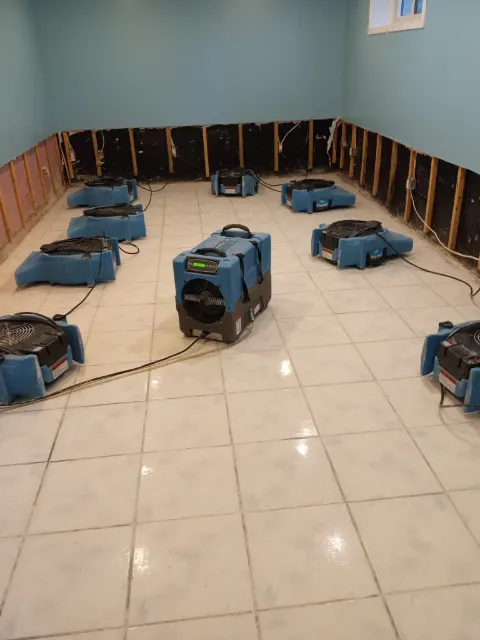 Eight air movers and a dehumidifier drying a tiled room after a flood cut