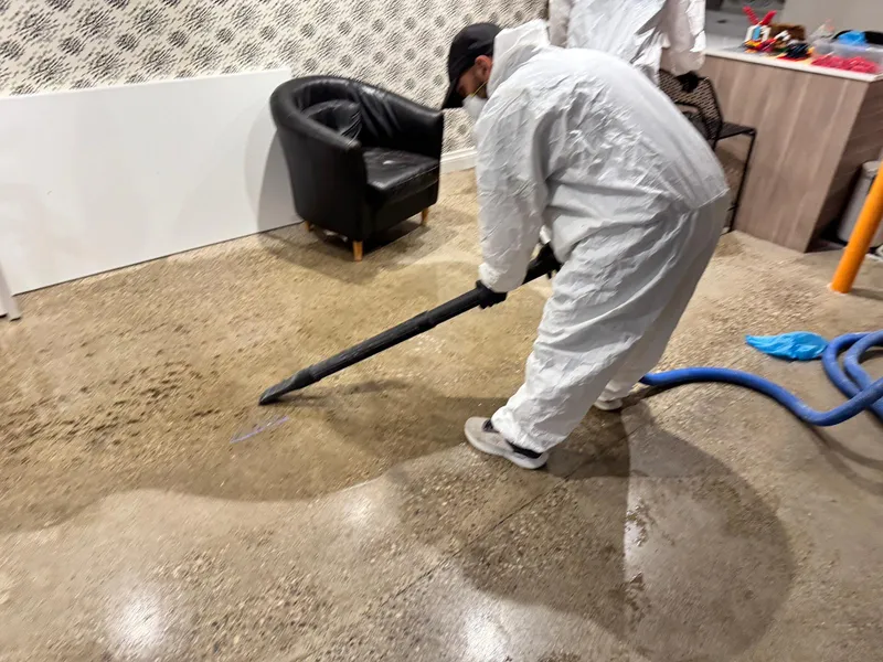 IICRC-certified tech in Tyvek extracting Category 3 water from a contaminated basement