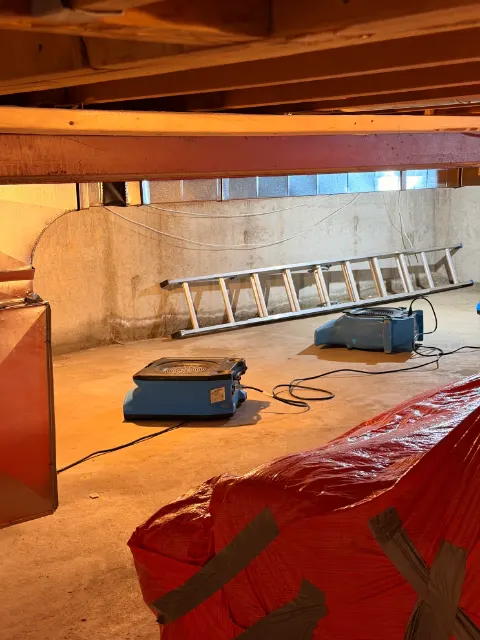 Air mover drying an unfinished basement with contents wrapped in plastic